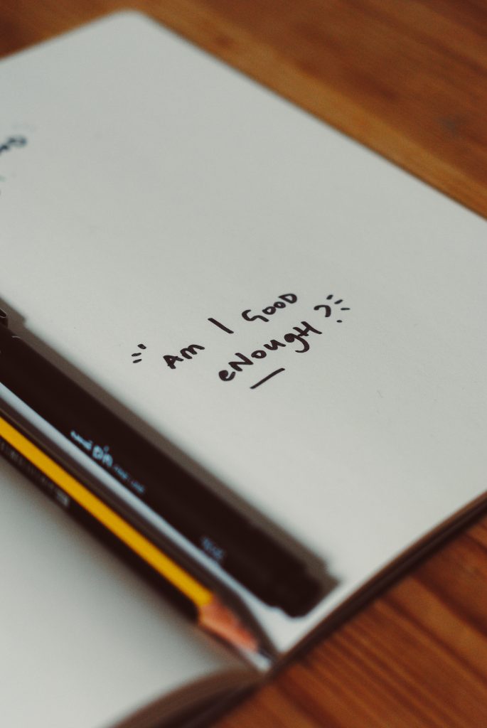 Notebook with text "am I good enough"