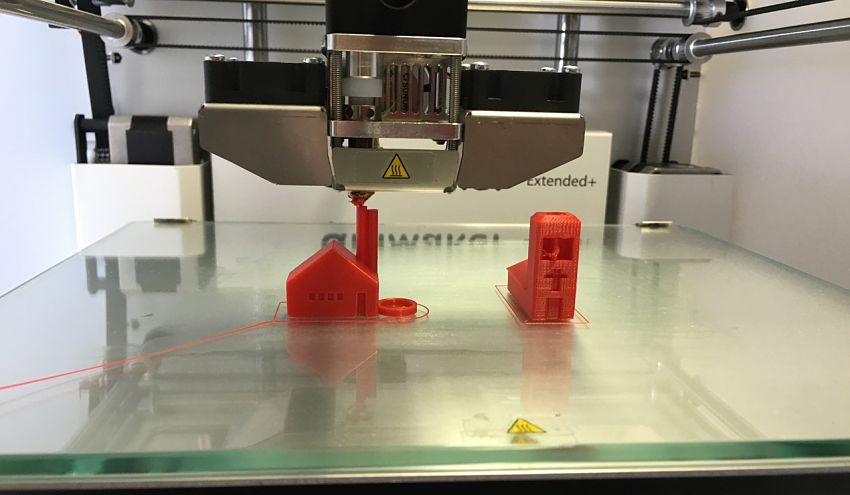 3D printer prints 2 miniature buildings