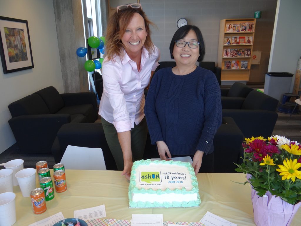 Portrait of two librarians from Durham College with an askON celebratory cake.