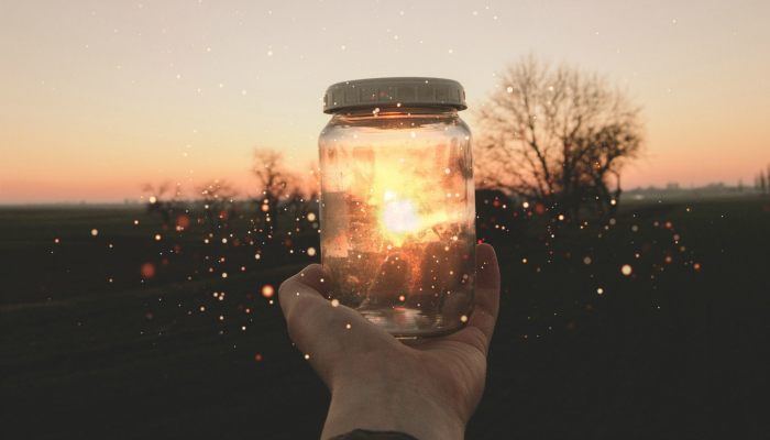 Fireflies In A Jar Being Held By An Outstretched Hand