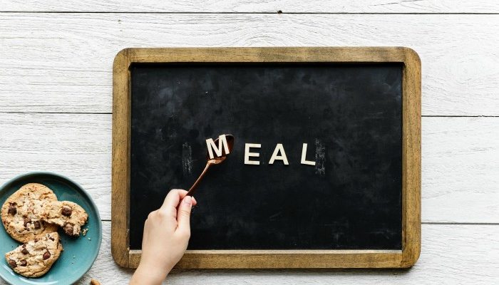 Plate Of Chocolate Chip Cookies And An Slate With The Word Meal Written On It.