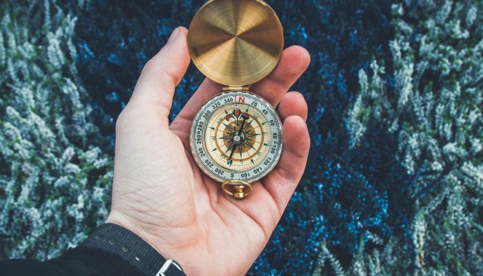 A Man's Hand Holding A Gold Compass