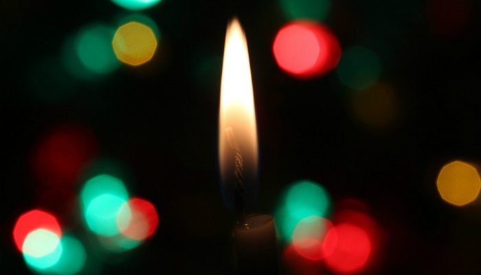Candle Burning In Dark Background With Red, White And Green Lights