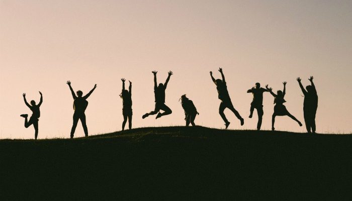 Silhouette Of Figures On A Mountain Jumping