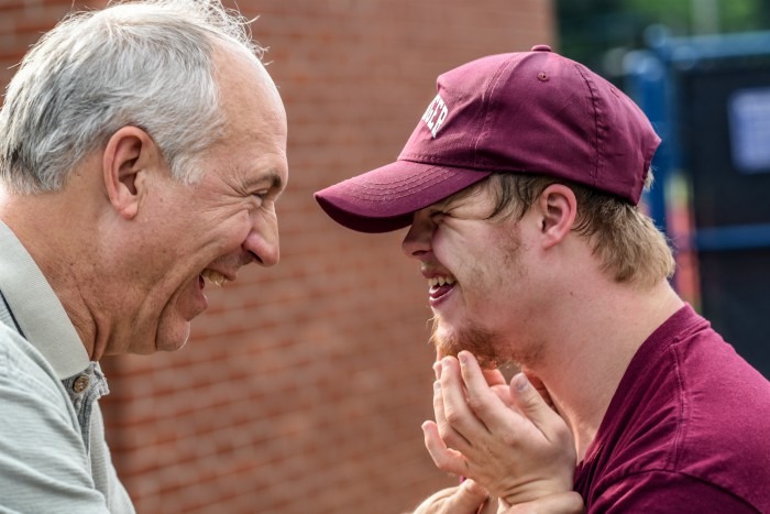 An older man on the left hugs a younger man on the right.