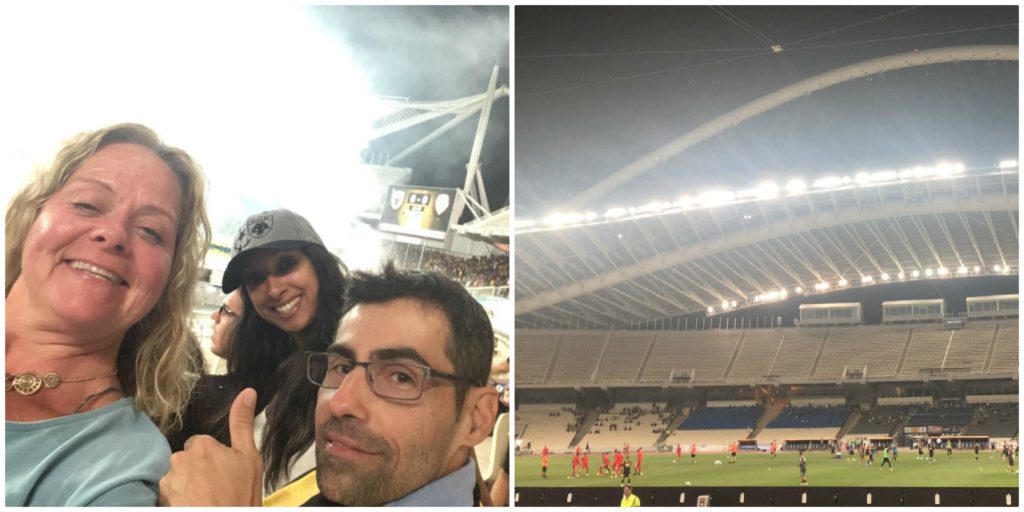 Sarah Shujah with two colleagues and a view of a football field in Athens