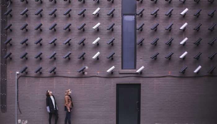 Two Women Underneath A Wall Of Video Cameras