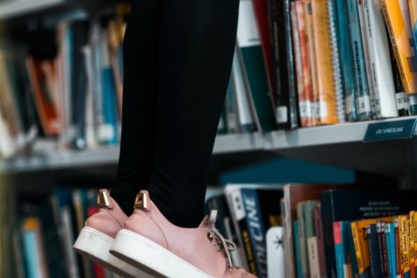 Girl Standing On Pile Of Books