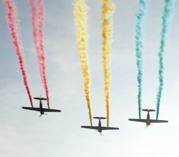 An aerial shot of three jets, each with different colour of exhaust.