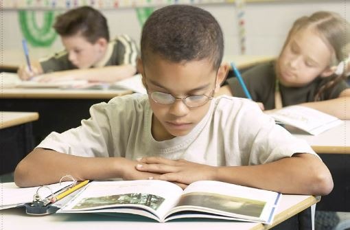 Young boy sitting at a desk reading