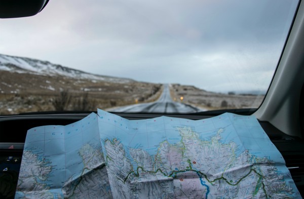 A road map open before a car windshield