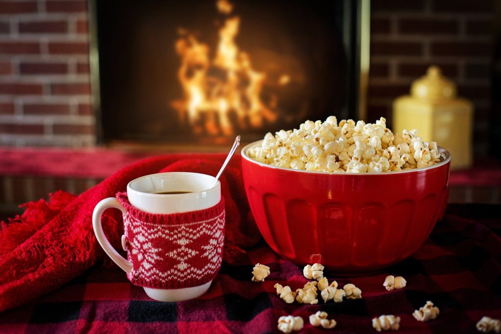 Hot drink and popcorn on a table, in front of a fire