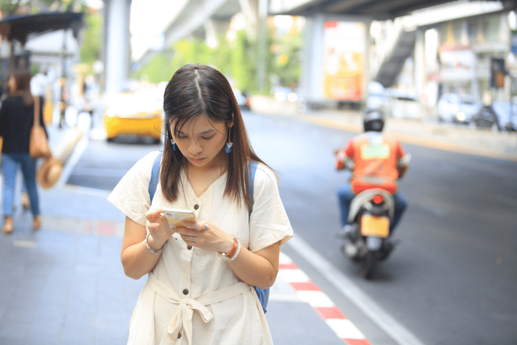 A woman walking down the street, intently staring at her phone