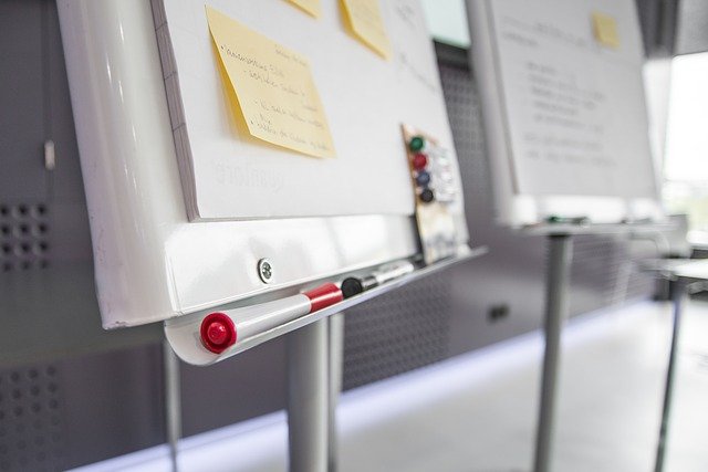 Whiteboard with sticky notes on it and dry erase markers sitting along the bottom