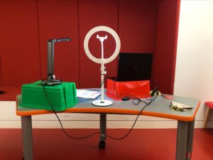 A streaming setup for digital library programming including a ring light, laptop and camera for easy display of books.