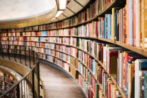 Books on brown wooden curved shelf.