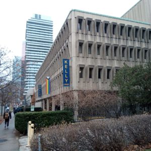 A photograph of a rectangular building with many rows of windows and a banner that says "Kelly".